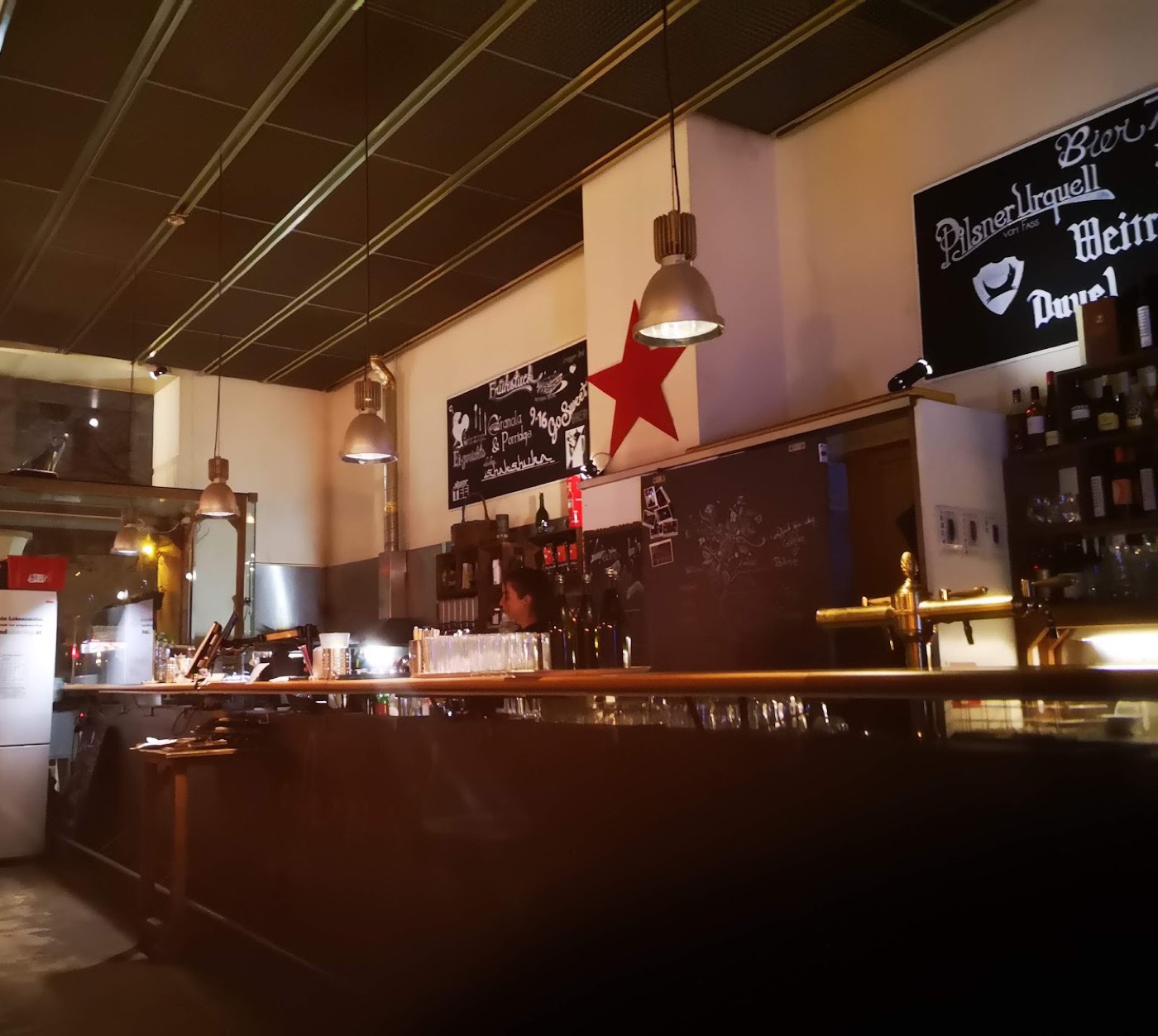 Bar des Cafe 7Stern am Abend mit rotem Stern, Kreidetafel und Pendelleuchten