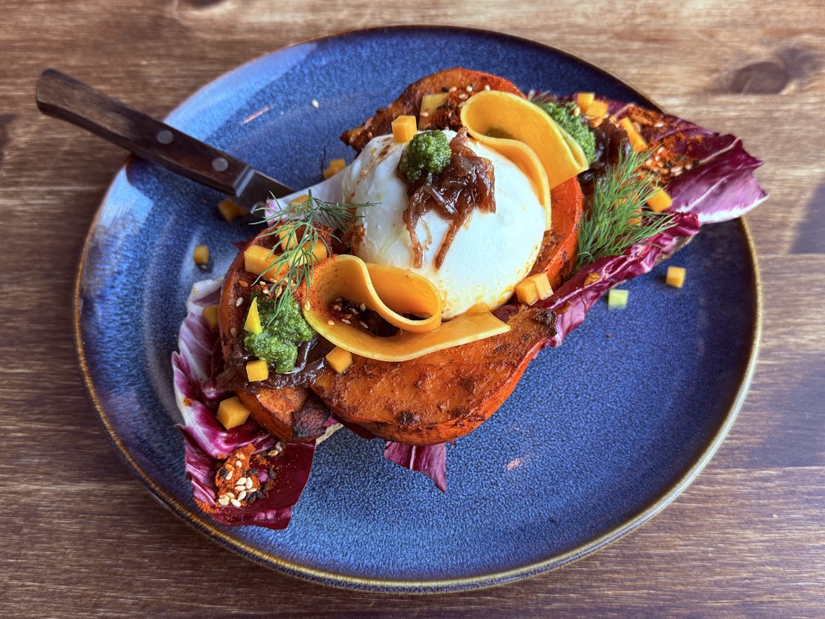 Kürbisbrot mit Burrata, Radicchio, Pesto und Dille auf einem blauen Teller